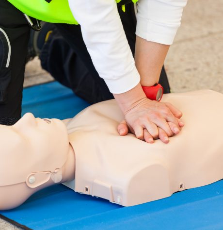 Female instructor showing CPR on training doll.