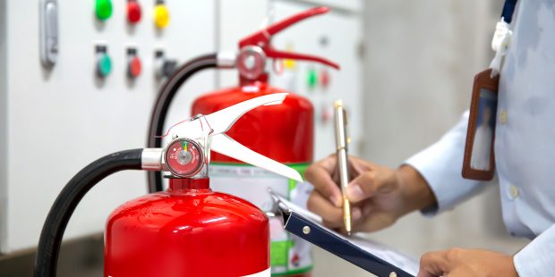 Engineer are checking and inspection a red fire extinguishers in the fire control room for safety prevention and fire training.